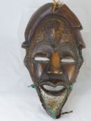 An African Stylised Wooden Tribal Mask, the mask fashioned with wire and staples, 44 x 24 cms.