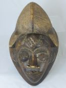 An African Stylised Wooden Tribal Mask, the mask fashioned with wire and staples, 45 x 29 cms.