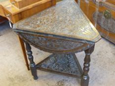 An Antique Oak Carved Envelope Table, the table carved with flowers to top and bottom shelf on