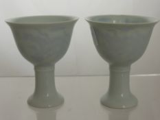 A Pair of Chinese Blanc de Chine Porcelain wine glasses, the glasses on stepped foot and having