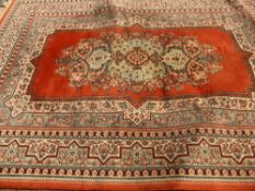 A Middle Eastern Style Woollen Rug, the rug having an orange ground with floral design to central