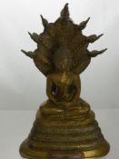 A Brass Indonesian Figure of Buddha seated in lotus position on top of a cobra, copper script