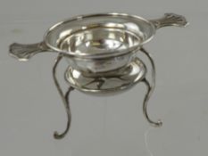 A Silver Tea Strainer and Stand, having pierced handles on wired tripod base, Birmingham hallmark,