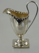 An Antique Silver Miniature Regency Style Sauce Jug, decorated with hammered edge on square foot,