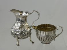 An Antique Silver Cream Jug, the jug with floral design on hoof feet, marks rubbed, together with