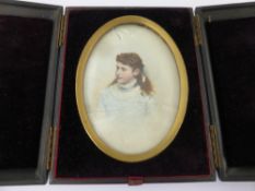 An Oval Victorian Portrait Miniature on Glass, depicting a young woman, in the original olive wood