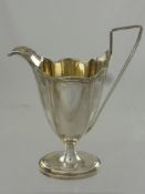 An Antique Silver Regency Style Sauce Jug, the sauce boat having rib form edge and handle on oval