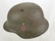 A WWII Waffen SS Helmet dated 1944 with original SS and Swastika decals, believed to be a M40