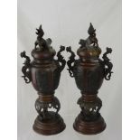 A Pair of Bronzed Composite Mantle Garniture Urns, with Fo Dog finials and sea serpent handles,