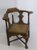 An Antique Oak Corner Seat, with decorative carving to the arm rests and back panel, cross