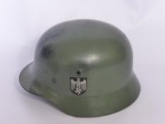 A WWII German Nazi Helmet, model M1940, with original paint and Nazi insignia to the side