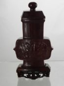 A Red hard Stone Vase and cover having taotie carving in relief to back and front approx 13.5 cms.