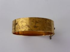 A 9 ct Gold Metal Core Bangle Bracelet, the bracelet engraved with a floral design.