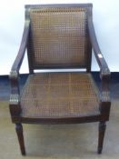 A Rattan Empire-Style Chair, with swept arms and turned legs.