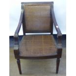 A Rattan Empire-Style Chair, with swept arms and turned legs.