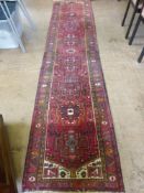 An Antique Persian Woollen Hall Runner, the runner with floral outer border and centre geometric
