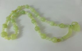 An Apple Green Jade Beaded Necklace, the carved necklace having a dragon form clasp, approx 60 cms