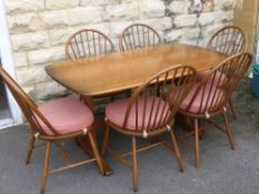 An Ercol 'Autumn' Gold Dining Table with six Latimer spindle back dining chairs.