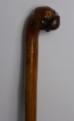 A Walking Cane, the knop carved as a pug's head having glass eyes, approx 90 cms long.