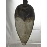 A Sub-Saharan African Tribal Mask, with a concave, heart shaped kaolin painted face, narrow slit
