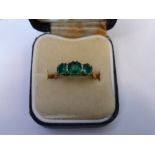 A Lady's 18 ct Yellow and White Gold 3-stone Emerald Ring, size P, centre emerald 5 x 5 mm, 2 x 4