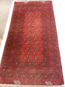 An Afghan Rug, with label of origin to one corner with central ghouls on cherry red ground, approx