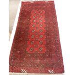 An Afghan Rug, with label of origin to one corner with central ghouls on cherry red ground, approx