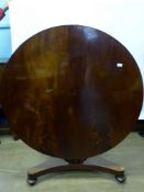 An Antique Circular Mahogany Tilt Top Dining Table, the table on column support with three feet on