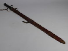 An Antique North African Sword, the sword having leather handle and tooled leather scabbard with