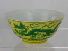 A yellow and green Chinese porcelain bowl painted with a leaping dragon among scrolling foliage