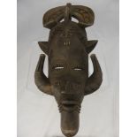 A Sub-Saharan Wooden Tribal Mask, depicted with horns from the lower jaw.