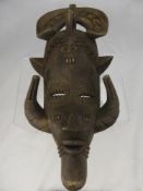 A Sub-Saharan Wooden Tribal Mask, depicted with horns from the lower jaw.