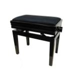 An adjustable piano stool raised on square tapered legs and finished in a black velvet upholstery