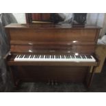 Hellas     C.1983 A modern upright piano in a walnut polyester case.