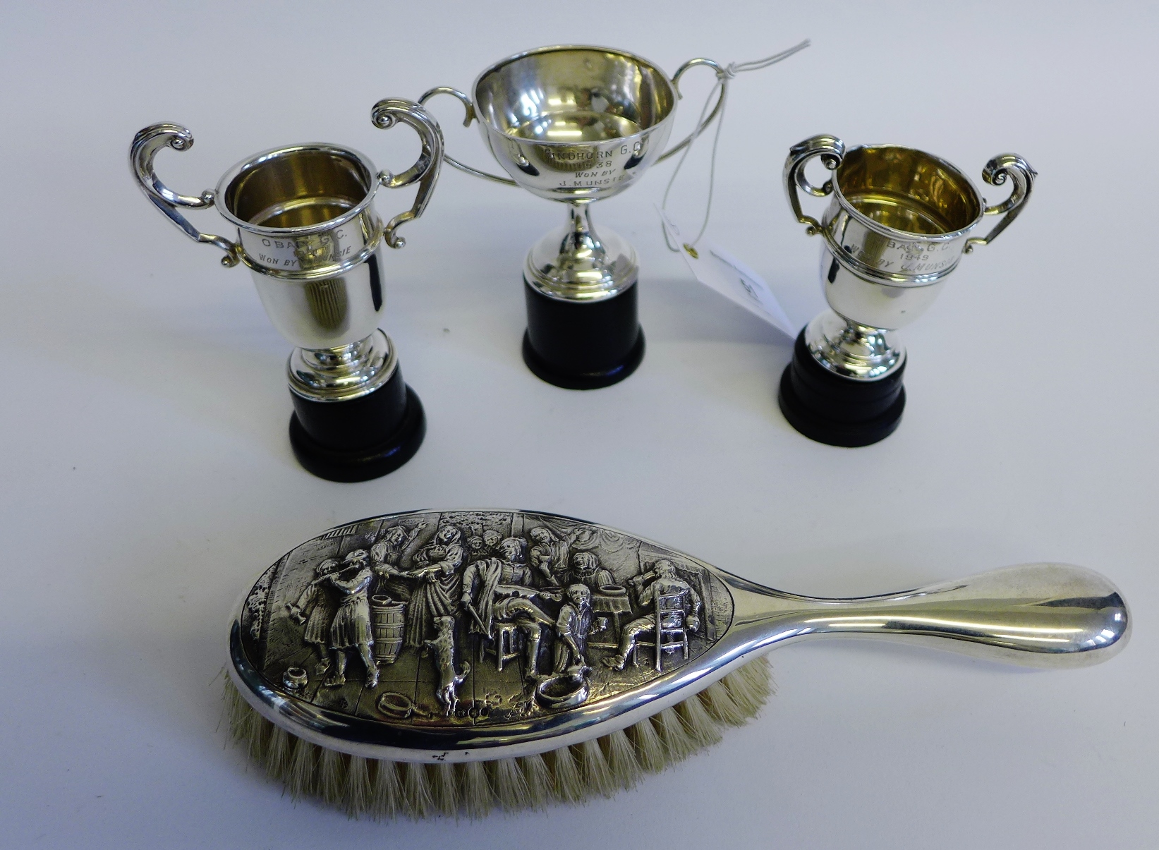 Three early 20th century silver miniature trophy cups, complete with ebonised stands together with a