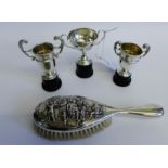 Three early 20th century silver miniature trophy cups, complete with ebonised stands together with a