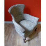 A late Victorian lounge chair upholstered in floral fabric raised on moulded feet