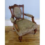 A late Victorian walnut easy chair having a carved top rail over padded back support over stuff over