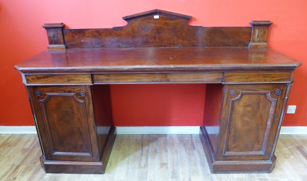A 19th century mahogany twin pedestal ledgeback sideboard having a moulded top over one long