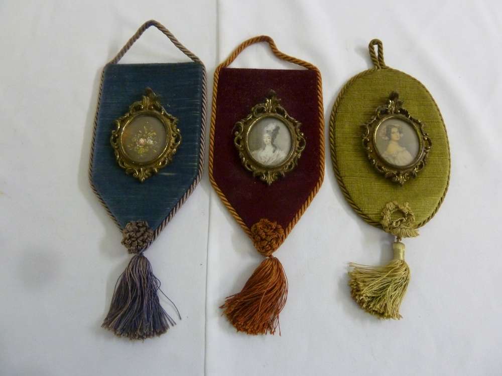 Three reproduction miniatures set on velvet wall mounts
