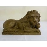 Wooden carving of a recumbent lion supporting a sphere