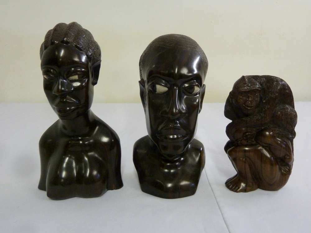 A pair of wooden carvings of African figures and a carved wooden figure of a man and  monkey