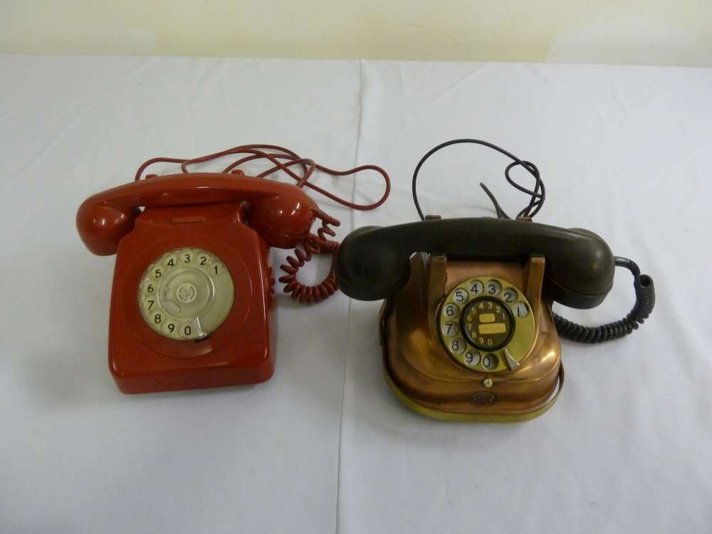 Two mid 20th century telephones one red plastic the other copper and brass