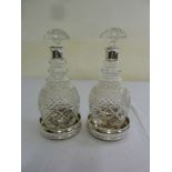 Pair of cut glass decanters with silver collars and two silver wine coasters