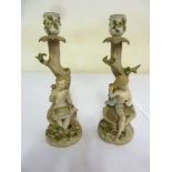 Pair of Continental porcelain candlesticks in the form of children beneath trees - marks to the base