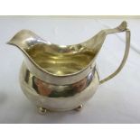 George III silver cream jug of bellied oval form on four ball feet with crest to the side, London