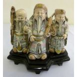 Three carved composition figures of Oriental elders on raised wooden stand