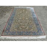 Persian silk carpet profusely decorated with flowers, animals and birds against a moss green