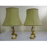 A pair of gilt metal and marble table lamps with cast putti supports on fluted columns with husk