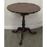 Mahogany pie crust revolving tilt top table on pedestal base, with three outswept feet